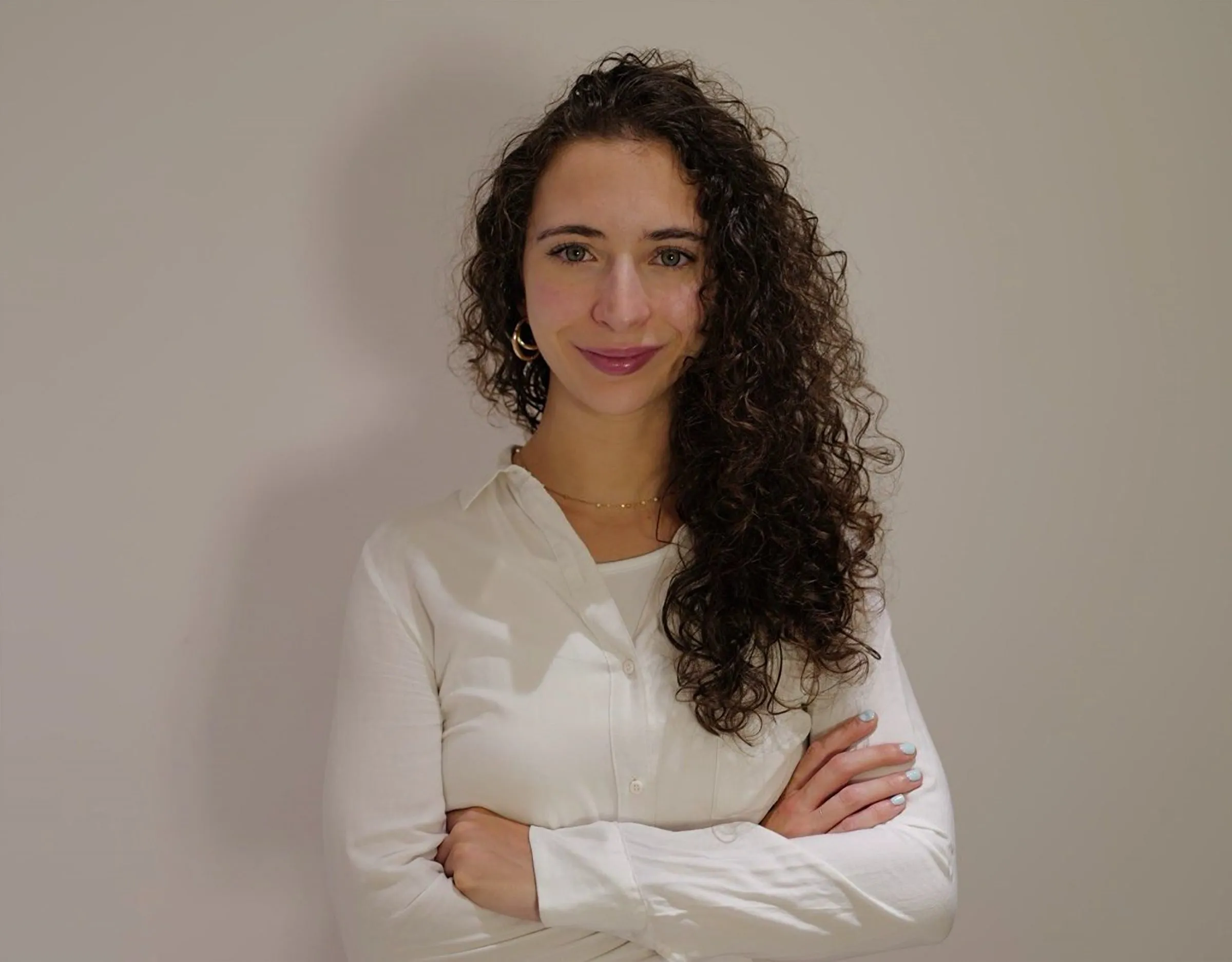 Teresa Villa in a white blouse, smiling, arms crossed