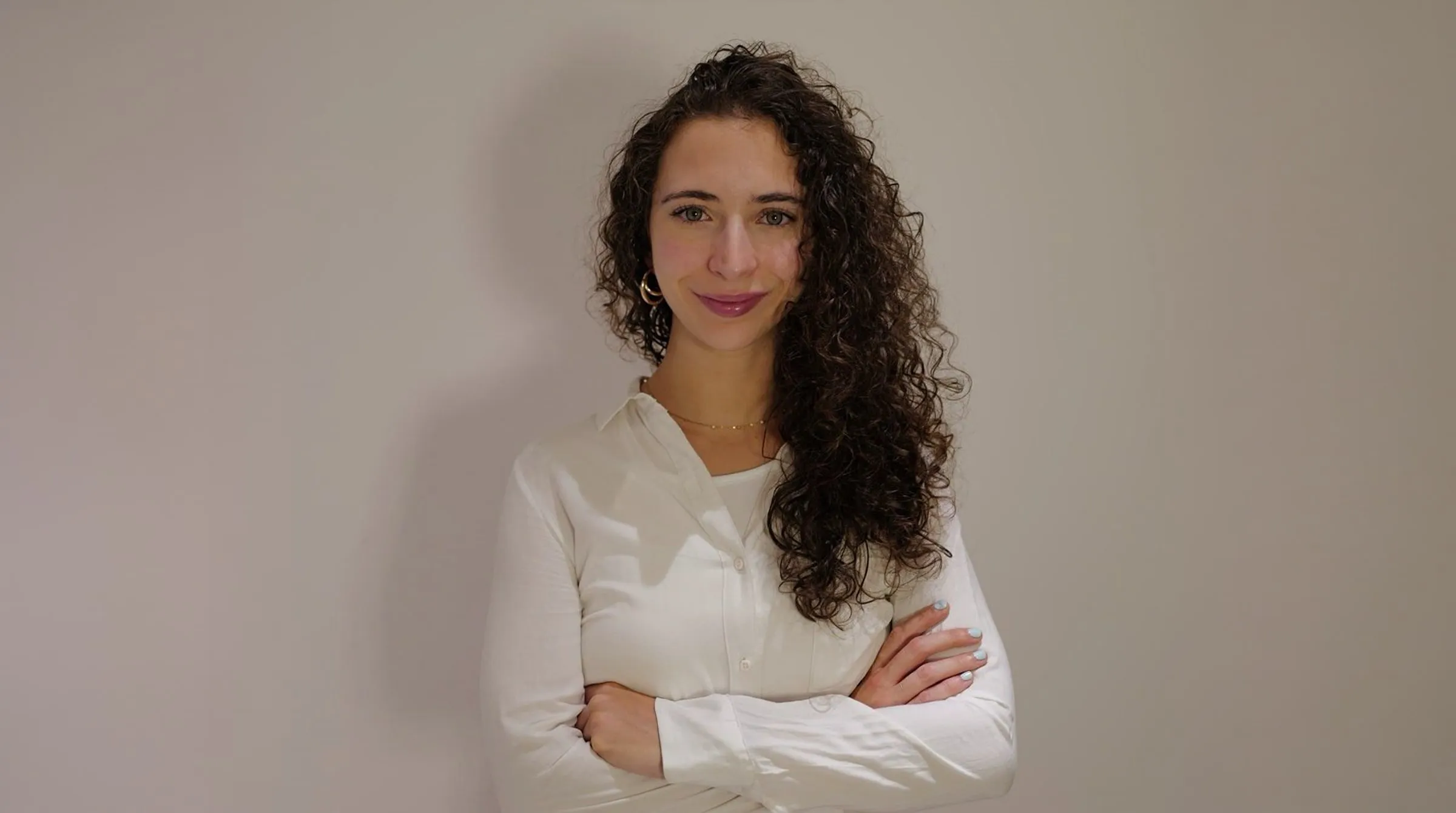 Teresa Villa in a white blouse, smiling, arms crossed